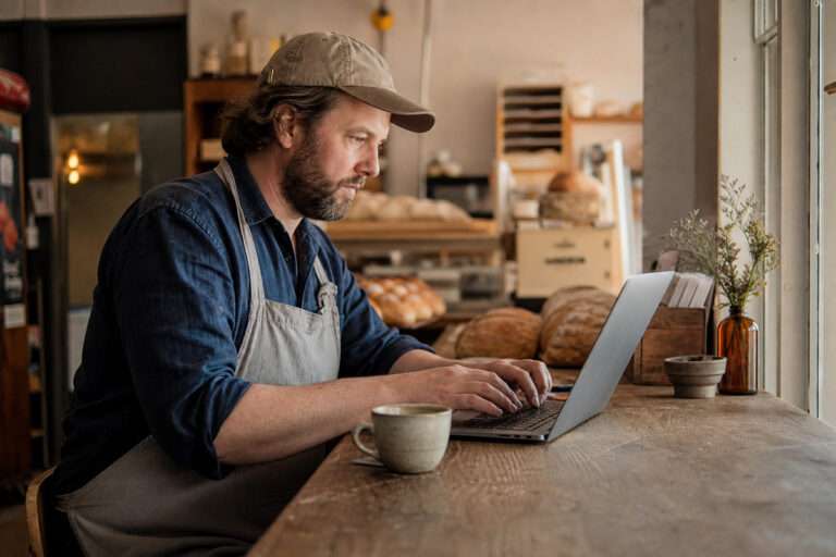 Betriebsinhaber tippt eine Frage in eine KI-Chat-App auf dem Laptop